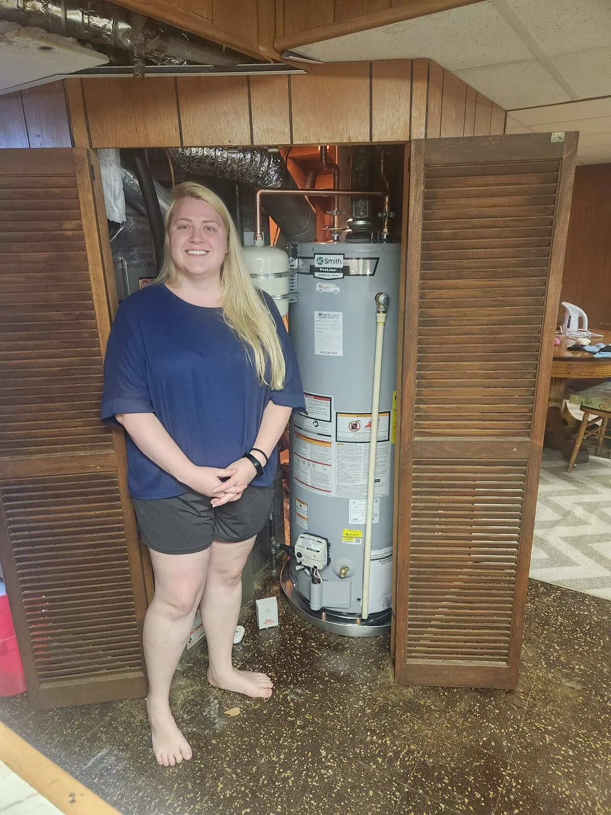 Brittany Alms standing beside her new AO Smith water heater in her Catonsville, MD home