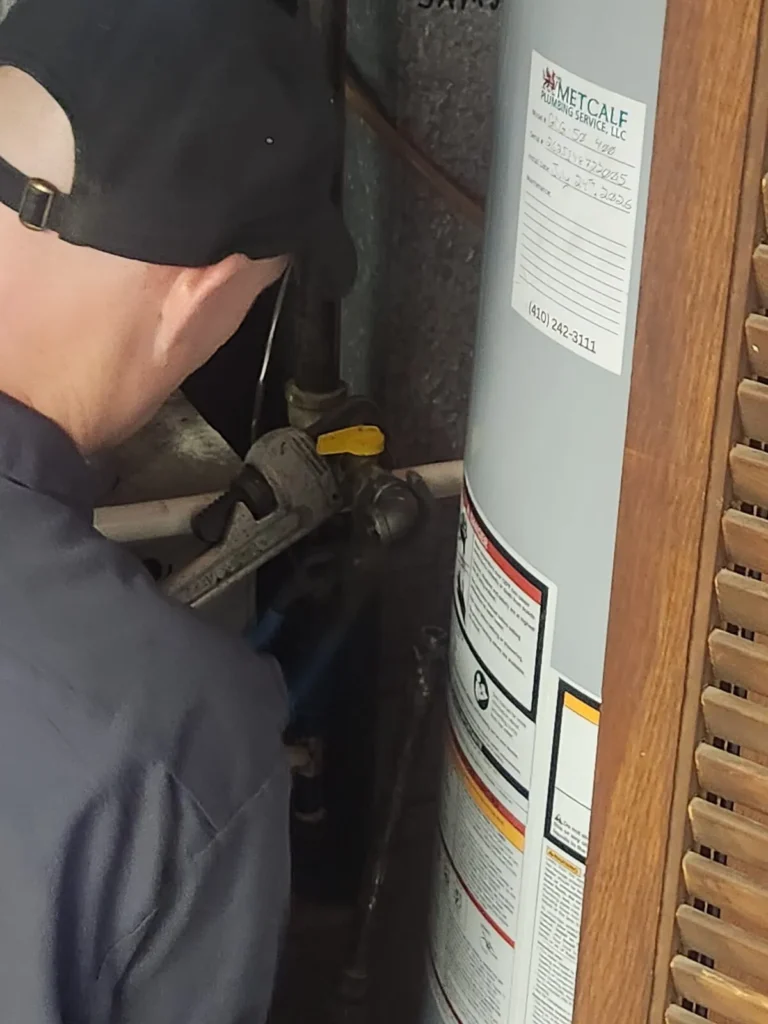 Metcalf Plumbing plumber tightening a fitting on the new AO Smith water heater